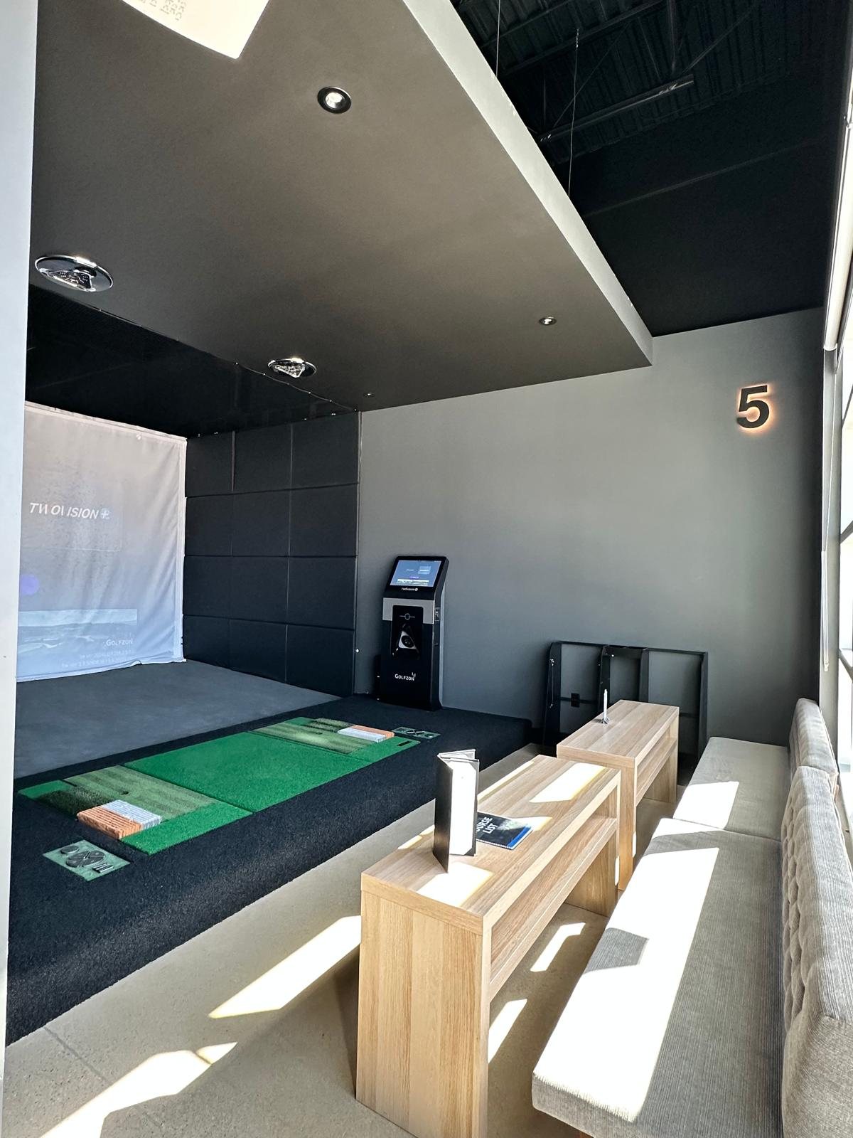 Bay 5, the private suite, with its simulator screen, hitting mat, touchscreen kiosk and bench seating